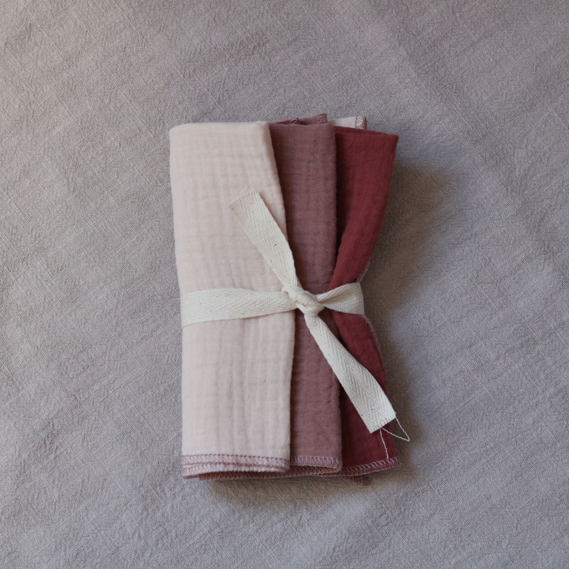 Zestaw pieluszek dla noworodka w kolorach kremu i różu, pakowane po trzy sztuki.